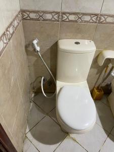 a white toilet in a bathroom with a hose at برج المحطة in Sharjah