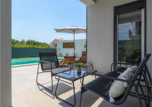 eine Terrasse mit Stühlen, einem Tisch und einem Sonnenschirm in der Unterkunft Villa Diva Istria in Nova Vas