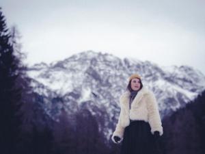kobieta stojąca przed pokrytą śniegiem górą w obiekcie Almwellness-Resort Tuffbad w mieście Sankt Lorenzen im Lesachtal