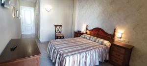 a bedroom with a bed and a dresser and a desk at Hotel El Doncel in Atarfe