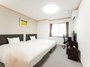 a hotel room with two beds and a television at Nasu Kogen North Inn in Higashikoya