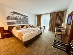 ボニャルツバシュにあるZenit Wellness Hotel Balatonのベッドとデスクが備わるホテルルームです。