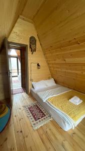 ein Schlafzimmer mit einem Bett in einem Holzzimmer in der Unterkunft AURA Cottages in Kazbegi