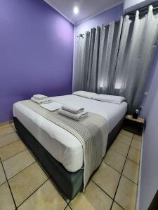 Habitación púrpura con 2 camas y toallas. en Nina Apartment, en La Canea