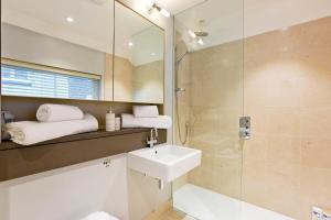 bagno con lavandino e doccia con specchio di 2 Bed Mews House Marylebone a Londra