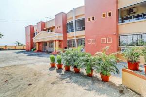 a red building with potted plants in front of it at Hotel Apratim Lodging & Boarding in Ambernath