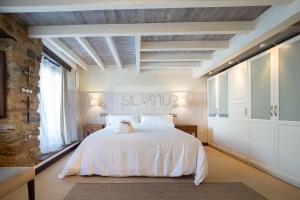 um quarto com uma cama branca e uma parede de pedra em El Gorin Casona em Gijón