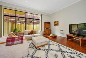 sala de estar con sofá y TV de pantalla plana en Bright & Eclectic Home - Footscray VIC, en Melbourne