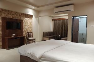a bedroom with a bed and a chair and a television at Hotel Apratim Lodging & Boarding in Ambernath