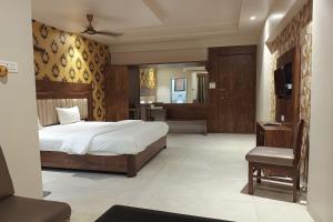 a bedroom with a bed and a chair and a television at Hotel Apratim Lodging & Boarding in Ambernath