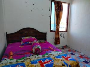um quarto com uma cama com lençóis roxos e uma janela em Atta Ratu Homestay em Komodo
