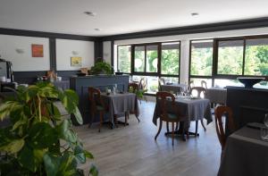 a dining room with tables and chairs and windows at Aubergade in Barbotan-les-Thermes