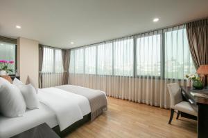 ein Hotelzimmer mit einem Bett, einem Schreibtisch und Fenstern in der Unterkunft HB Serviced Apartment - 121B Quan Hoa in Hanoi