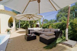 un patio con sofá y sombrilla en Villa Jasmim, en Almancil