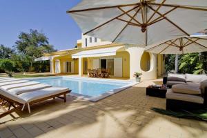 ein Haus mit einem Pool mit Sonnenschirm in der Unterkunft Villa Jasmim in Almancil
