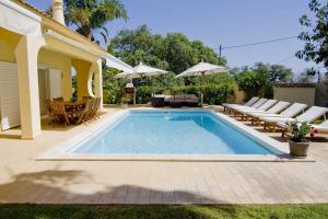 einen Pool im Hinterhof mit Stühlen und einem Sonnenschirm in der Unterkunft Villa Jasmim in Almancil