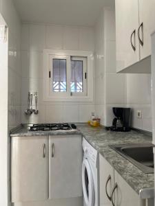 een witte keuken met een fornuis en een vaatwasser bij Gestión Inmobiliaria Carmona Rent in Benidorm
