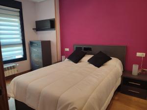- une chambre avec un grand lit et un mur rose dans l'établissement Apartamento Florida-Natura Oviedo, à Oviedo