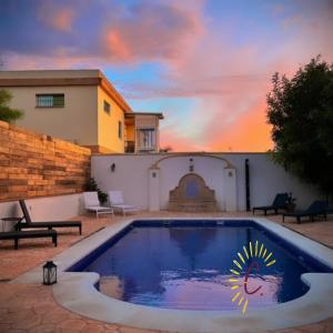 a pool in a yard with a sunset in the background at casa de vicky in El Puerto de Santa María