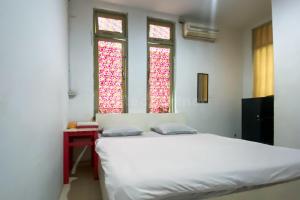 1 dormitorio con 1 cama blanca y 2 ventanas en Wisma Syariah Lambhuk Banda Aceh RedPartner, en Banda Aceh