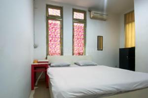 a bedroom with a white bed and two windows at Wisma Syariah Lambhuk Banda Aceh RedPartner in Banda Aceh