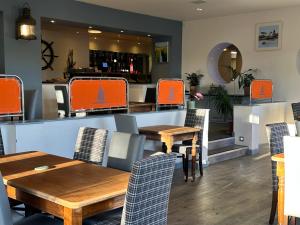 a restaurant with wooden tables and orange chairs at Waveney Inn & Hotel in Burgh Saint Peter