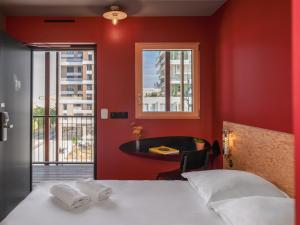 a bedroom with red walls and a bed and a table at Eklo Toulouse in Toulouse