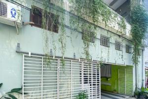 a white building with a gate and ivy on it at Wisma Syariah Lambhuk Banda Aceh RedPartner in Banda Aceh