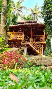 ein Bambusgebäude mit Palmen im Garten in der Unterkunft Nawgala Eco Cottage 