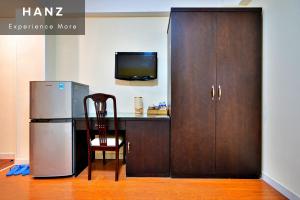 a refrigerator and a table with a desk and a television at HANZ Sai Gon Hotel Bui Vien Alley 40 in Ho Chi Minh City