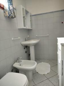 a white bathroom with a toilet and a sink at Oasi Boungaville in Porto San Paolo +5 photos