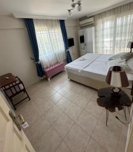 a bedroom with a bed and a table and a chair at Hotel Antonio in Çeşme
