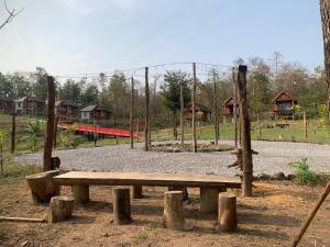 un banc en bois dans un parc avec une aire de jeux dans l'établissement Happiness Long Bridge Resort, 