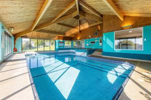 a large swimming pool in a building with a wooden ceiling at Waveney Inn & Hotel in Burgh Saint Peter