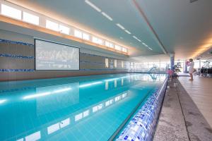 a large swimming pool in a building with a tv at Zenit Wellness Hotel Balaton in Vonyarcvashegy