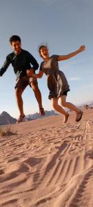 a man and a woman jumping in the sand at Omar Camp Wadi Rum in Disah