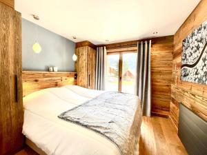 een slaapkamer met een bed met houten wanden en een raam bij Résidence Ancolie in Champagny-en-Vanoise