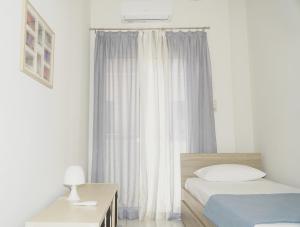 a bedroom with a bed and a window with curtains at Elegant central apartment in Heraklio Town