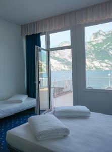 two beds in a room with a view of the ocean at Lake Hotel Ifigenia in Nago-Torbole