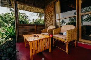 Habitación con porche con mesa y sillas. en Maisara Mafia Beach Lodge en Kilindoni