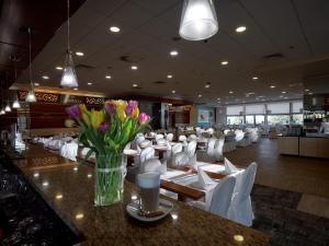 a restaurant with white chairs and a vase of flowers on a counter at Miejsca noclegowe w Arka Medical SPA in Kołobrzeg