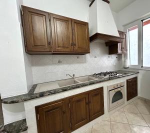 a kitchen with wooden cabinets and a stove top oven at Appartamento Deluxe I Cigni - Forio Ischia in Forio d'Ischia