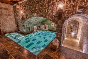 an indoor pool in a castle with a stone wall at Museum Hotel in Uçhisar