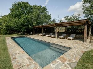 a swimming pool with a gazebo and chairs next to it at Hotel Castell de Vallgornera in Girona