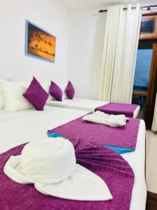 Lake Face Hotel في أنورادابورا: غرفة في الفندق بسريرين مع ملاءات أرجوانية ومناشف