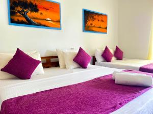 Lake Face Hotel في أنورادابورا: غرفة نوم بسريرين مع وسائد أرجوانية