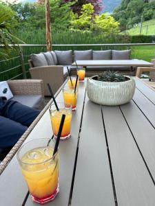 a wooden table with four glasses of orange juice on it at Hotel Garni Partaneshof in Merano