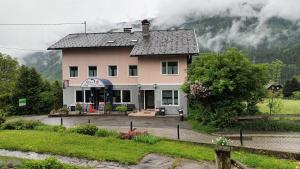 una grande casa rosa con montagne sullo sfondo di Haus Kolbnitz a Unterkolbnitz