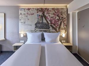 a bedroom with a large white bed with two pillows at B&B Hotel Bonn-City in Bonn