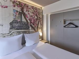 a bedroom with a white bed with a painting on the wall at B&B Hotel Bonn-City in Bonn